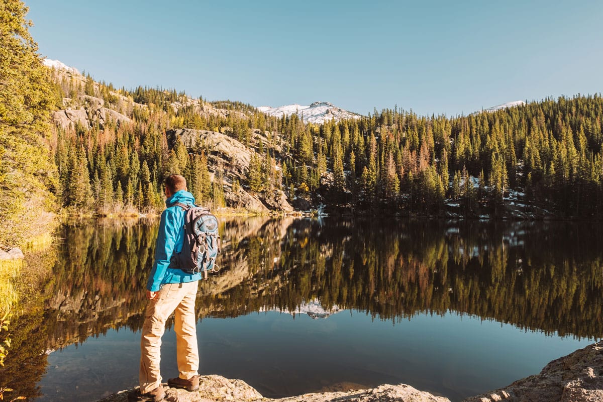 hiker stands in front of a high alpine lake near Breckenridge