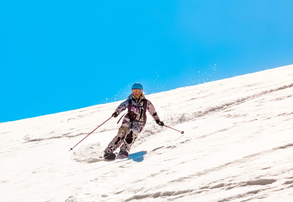 Woman skiing turns in the soft spring snow against a bright clear blue sky