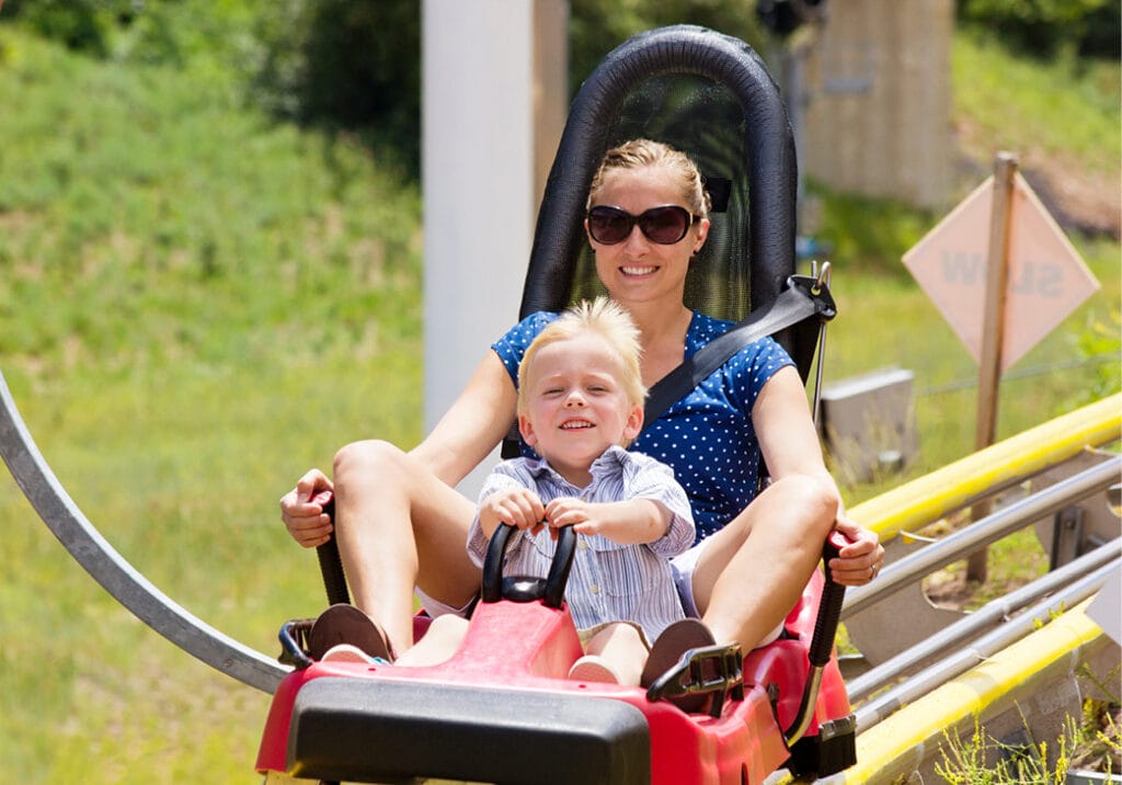Mother and son smiling riding alpine slide