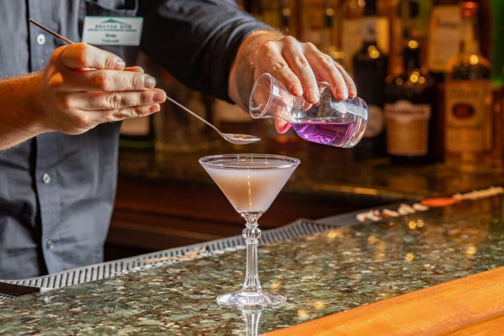 cocktail action shot of pouring a secret purple liquid
