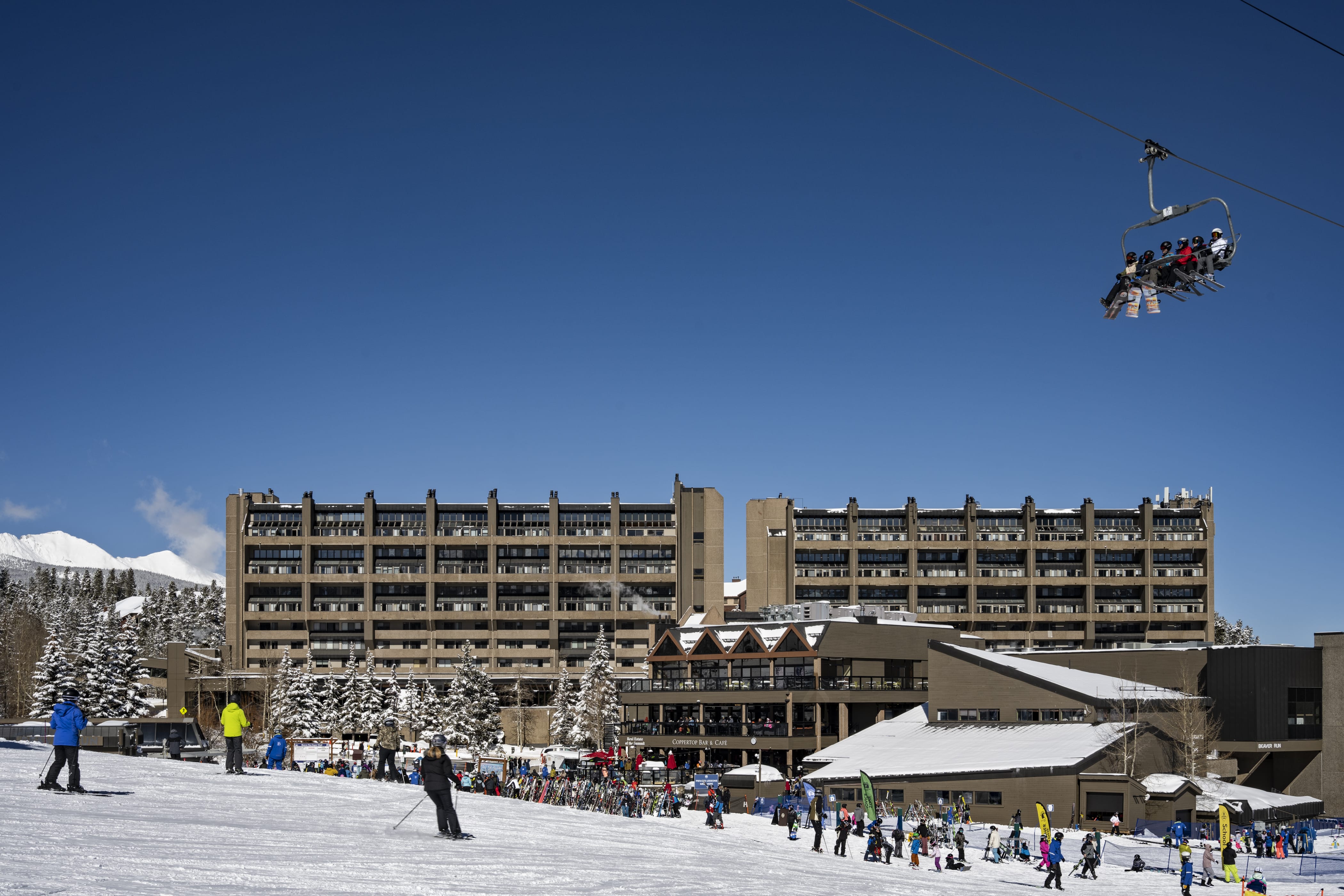 Skiers and snowboarders enjoying themselves at Peak 9 under the Beaver Run SuperChair and next to Beaver Run Resort.