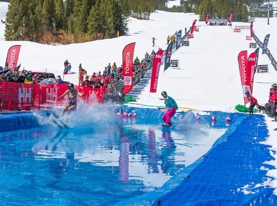 Two people skimming over a pond on skis